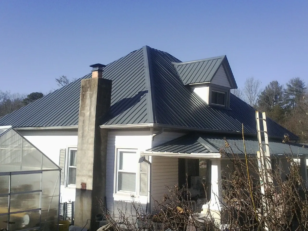 Dark blue standing seam metal roof on a white farmhouse with dormer — Slate & Tile Roof Repair by Roofing Brothers in West Barnstable