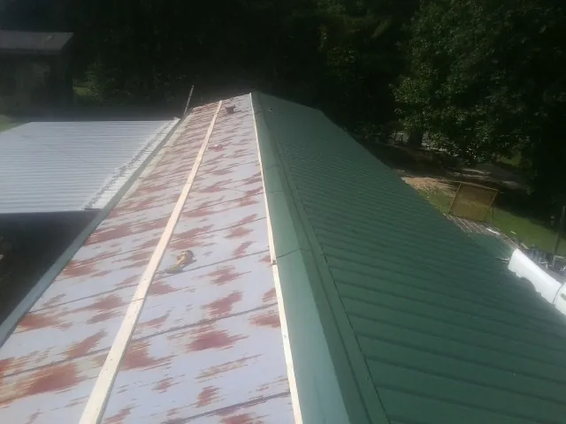 Old rusted panels beside newly installed green metal roofing — Wind Damage Roof Repair by Roofing Brothers in West Barnstable