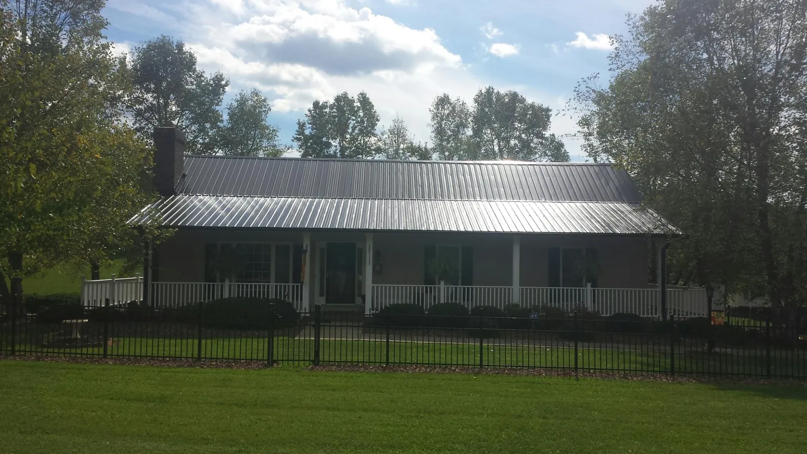Gray metal roof on a brick ranch with a full width front porch — Gutter Guard Installation work by our crew in West Barnstable