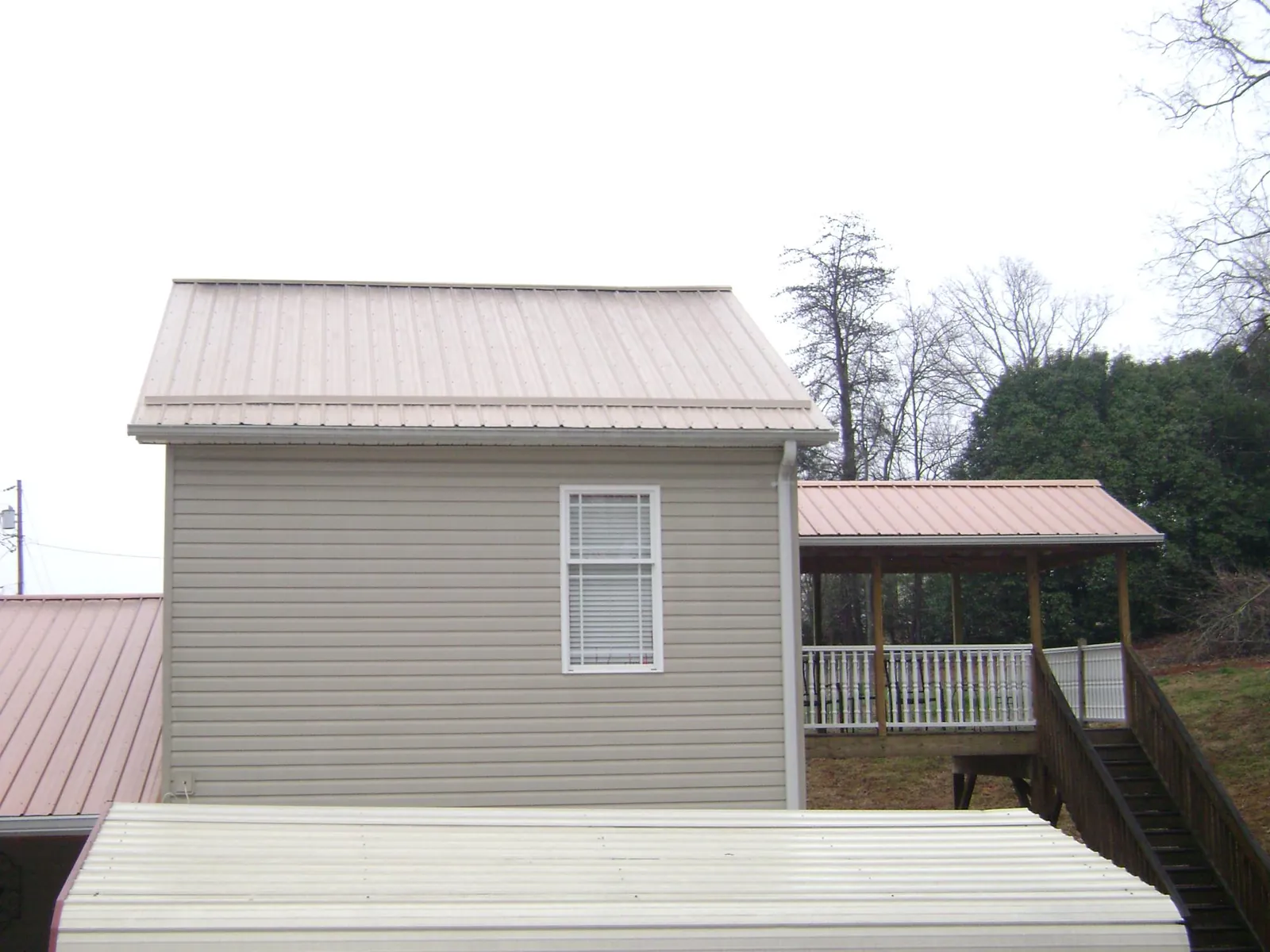 Tan metal roofs on a two story addition and attached porch, from a Roof Replacement job in West Barnstable
