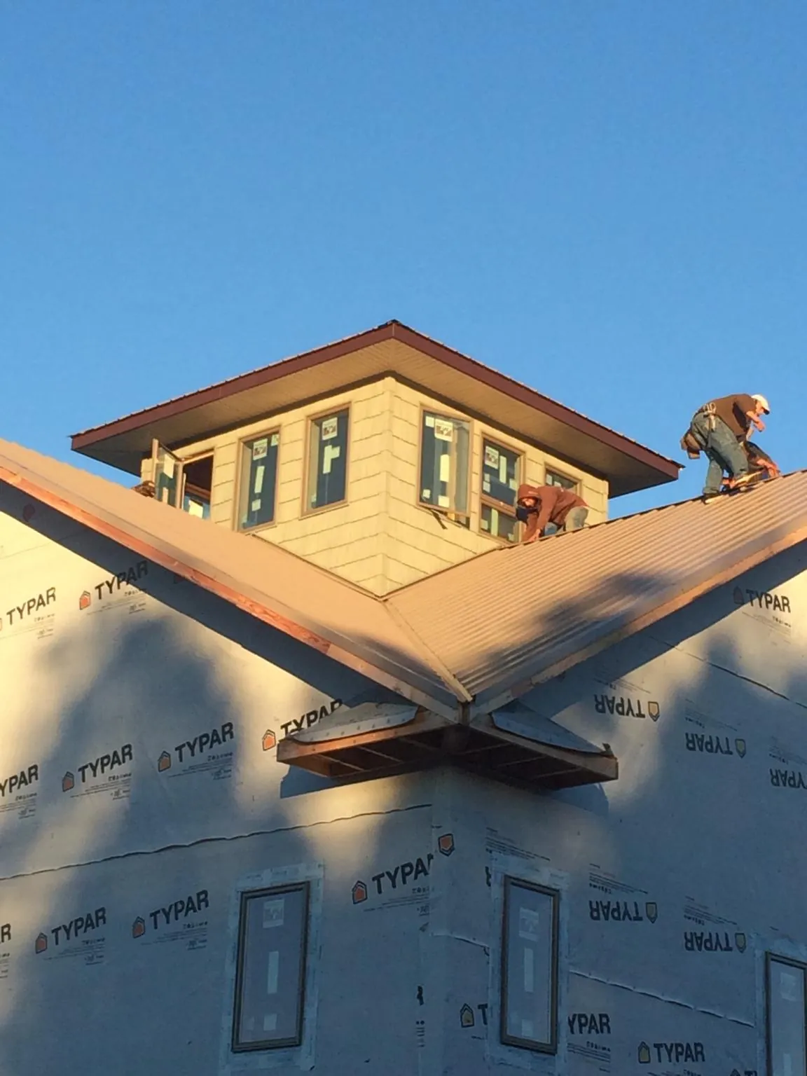Roofers working around a rooftop cupola on a new metal roof at sunset — Roof Waterproofing in West Barnstable by Roofing Brothers